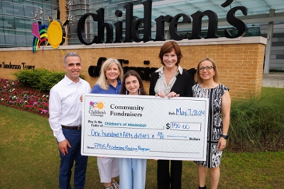 Antonina Karam, center, presents her gift to Children's of Mississippi with, from left, her father, Dr. Simon Karam; First Presbyterian Day School library Jana Heimer; Dr. Mary Taylor, Suzan B. Thames Chair and professor of pediatrics; and her mother, Dr. Rola Abi Selah.